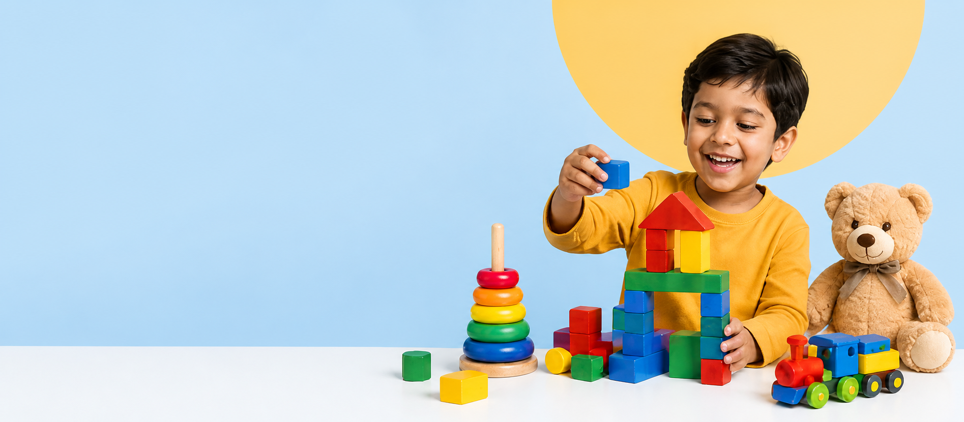 Child building a colorful toy tower with a teddy bear, stacking rings, and toy train